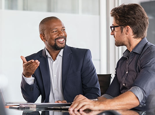 Businessman smiling and talking to his client in a conference room.