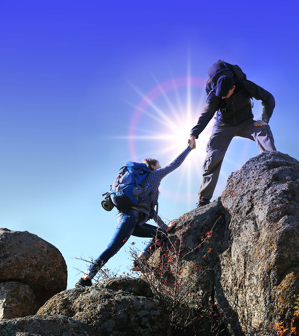 One mountain climber helping a second up the rocks